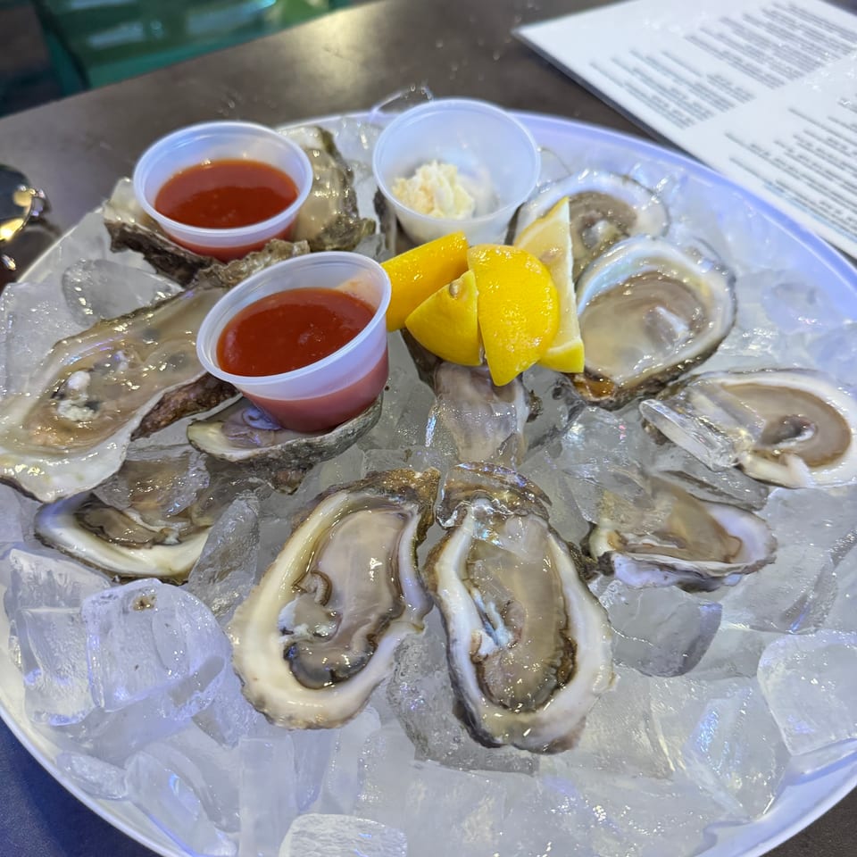 A dozen fresh oysters on the half shell, served on ice with lemon wedges and cocktail sauce.