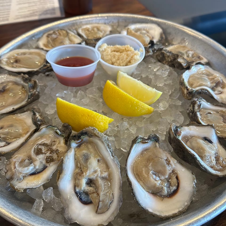 A dozen fresh oysters on the half shell, served on ice with lemon, cocktail sauce, and horseradish.